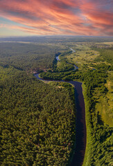 Obraz premium View from drone, panorama view of the forest and fields, top view, orange sky and gray clouds, sun at sunset