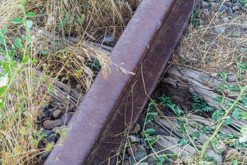 Obraz premium Old abandoned, unused railway line is falling into oblivion. Due to lack of maintenance, driving, the embankment is overgrown with wild grass, the sleepers are turning into dust, rails are corroding