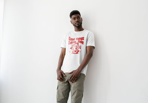 Mockup Of Man Wearing Customized T-Shirt Against Wall In Studio