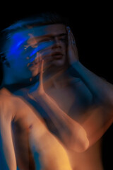 blurred silhouette, young man posing in the dark with red and blue light in the studio