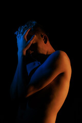 Young man posing in the dark with red and blue light in the studio