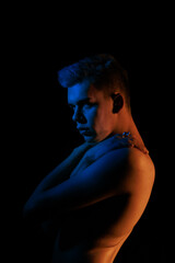 Young man posing in the dark with red and blue light in the studio