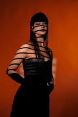 Brunette girl posing in a beam of light in the studio, on a red background, light and darkness.