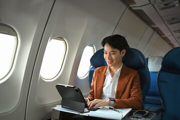 Successful businessman in elegant suit working with digital in aircraft during business travel