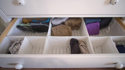 The process of laying out children's things and clothes in a chest of drawers, time lapse. Organizing order with clothes in the closet