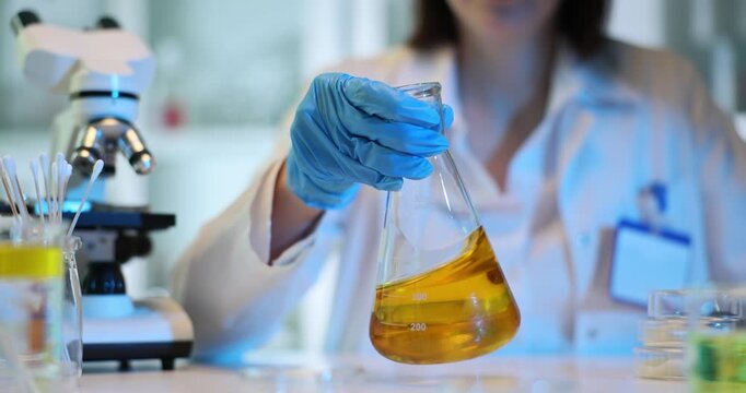 Scientist holding flask with yellow liquid in the laboratory