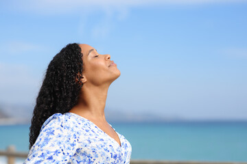 Serious black woman breathing fresh air on the beach