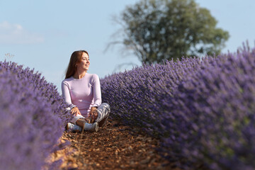 Woman sitting in lavender field contemplating and relaxing