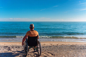 Fototapeta premium A person in a wheelchair enjoys a peaceful moment on a wooden boardwalk at a sunny beach, facing the ocean. The image captures the serene beauty of nature and the concept of accessibility and inclusio