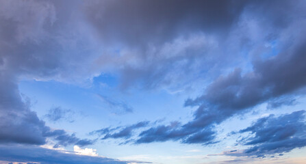 A breathtaking view of the sky filled with fluffy clouds reflecting soft colors as dusk settles over a serene landscape.