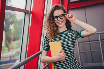 Fototapeta premium Photo of pretty young girl striped dress hold book touch glasses work study office business center