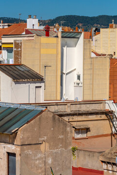 An urban scene featuring rooftops and various buildings with colorful facades and detailed architectural elements, capturing the essence of city life and design diversity in Barcelona Spain