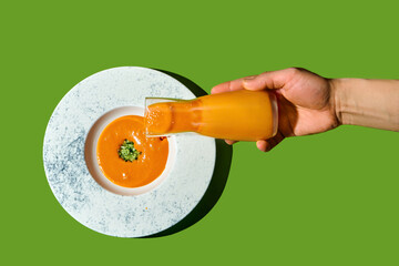 bowl of creamy pumpkin soup garnished with herbs. soup served on white plate on green background.