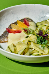 minimalist food photography composition featuring a seared sea bass fillet on bed of zucchini ribbons