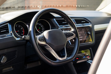 Car steering wheel, interior view of modern car and black dashboard with sun light.