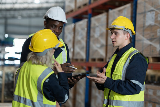 Warehouse worker working in warehouse. Male and female worker discussing at warehouse