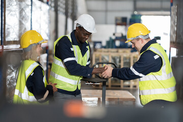 Warehouse worker working in warehouse. Male and female worker discussing at warehouse
