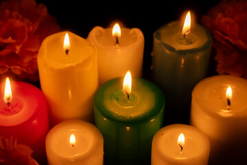 Candles burning brightly in the center, surrounded by marigolds on a dark background