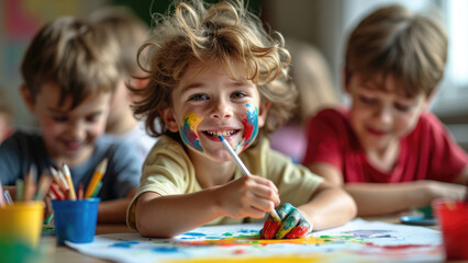 A happy child with colorful face paint is joyfully painting a picture at school, surrounded by classmates engaged in art activities at a lively classroom.