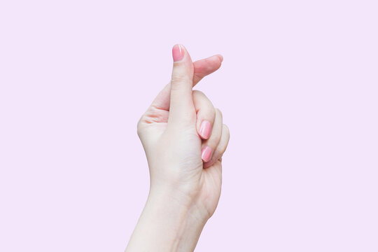 Beautiful female hand shows finger and hand like mini heart shape Korea style as a sign of love while isolated on pink background.