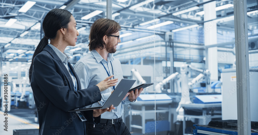 Leinwandbilder Portrait of Cheerful Engineer and Happy Asian Scientist Using Laptop and Tablet Computers, Talking in a Factory Facility with Robots Producing Modern Electronic Components for Different Industries