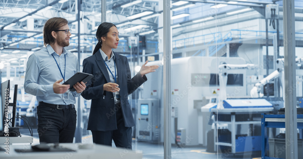 Poster Two Diverse Engineers Walking in Office, Using Tablet Computer at an Electronics Factory. Female and Male Specialists Chatting, Monitoring Robots on a Modern Assembly Line