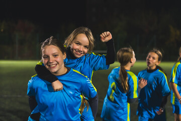 cute little girls with soccer uniforms taking photos before practice in the evening, football stadium. High quality photo