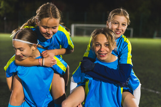 two tenage footballer girls carrying their teammates with their backs, team sport concept. High quality photo