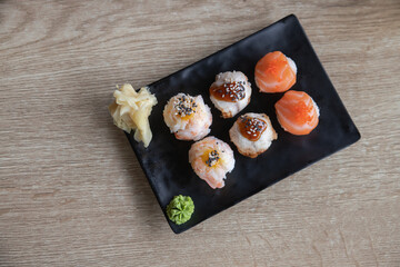 Temarizushi or Japanese rice balls served on the black plate in the restaurant Temari zushi with shrimp, crab, salmon, eel. Japanese Temarizushi. Selective focus.