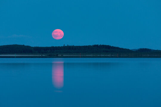 The red Moon rises over the lake