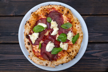 Italian Pizza Manzo in a plate on a wooden table.