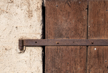 Old iron hinge on wooden gate. Rural architecture. Eclectic house in the countryside. Rusty metal elements, Construction details. Wooden door.
