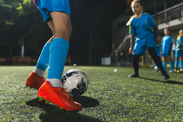 closeup shot of a girl playing with a soccer ball in a stadium, evening practice, blue uniforms....