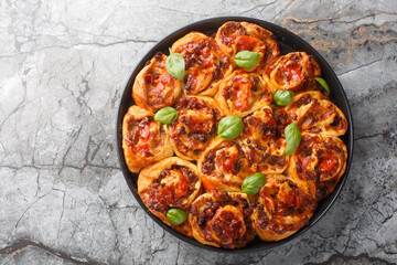 Rustic Pizza rolls filled with italian sausages, Mozzarella, tomato and basil closeup on the bakong dish on the table. Horizontal top view from above