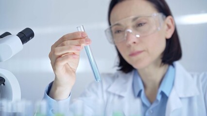 Scientist female researcher with protective glasses examining la