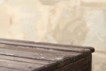 Wooden plank table with blurred concrete wall background, selective focus. Empty old table and wall for product display or installation