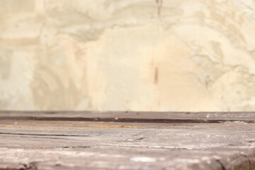 Wooden plank table with blurred concrete wall background, selective focus. Empty old table and wall...
