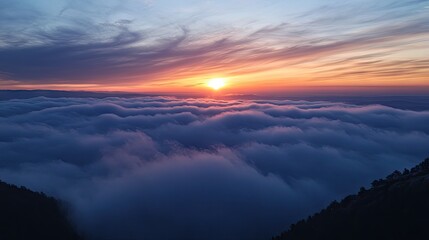 A view of clouds glowing with the last light of the day, as the sun sets below the horizon.