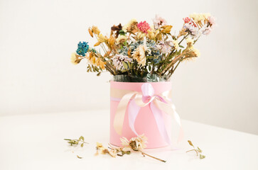 Fading flowers in pink vase on table at home. Dried flowers.