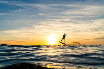 Silhouette of Kitesurfer performing jump in sunset conditions at the baltic sea