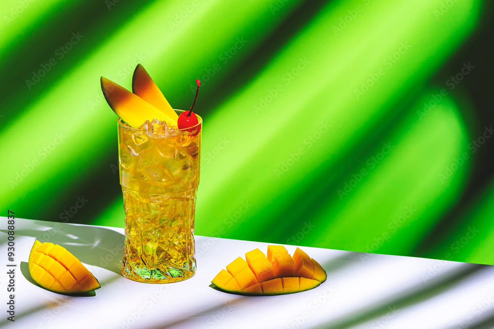 Wall mural Mango and rum alcoholic cocktail drink with syrup, ginger beer, lemon juice and ice. Green background, hard light