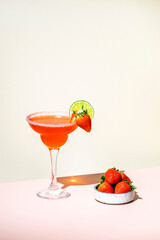 Strawberry summer red cocktail drink with tequila, limу juice, liqueur, berries and ice in glass. Beige background., hard light