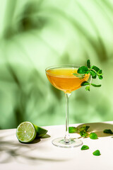 Summer alcoholic cocktail drink with rum, lime juice, dry sparkling wine, syrup, bitter, mint and ice, green background, hard light