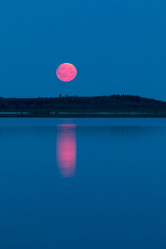 The red Moon rises, reflecting in the water