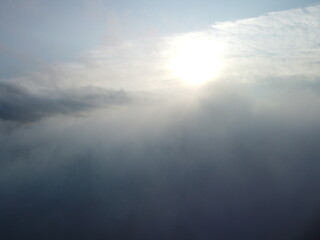 Naklejka premium Aerial view. Blue sky sun and fog over calm sea. The drone flies over foggy and fluffy clouds. Abstract aerial nature summer ocean sunset sea and sky background. Vacation, travel and holiday concept.