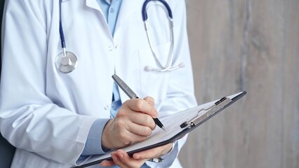 Healthcare professional doctor writing medical records on a clipboard. Female unrecognizable physician at work. Medicine and pharmacy