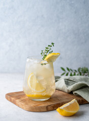 Mojito cocktail with fresh lemon, mint and ice. Refreshing citrus lemonade drink on a wooden board on a light background with napkin.