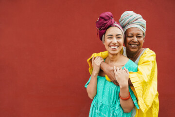 Fototapeta premium Happy african mother and daughter wearing traditional clothes - Motherhood, ethnic cultures and family concept - Focus on faces