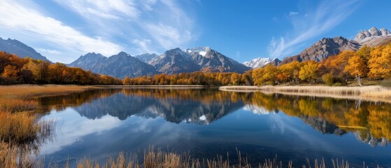 Fototapeta premium A body of water enveloped by mountains, a forest bursting with orange and yellow trees Sky dotted with clouds