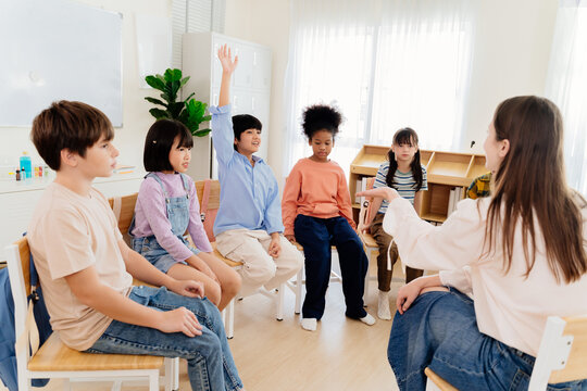 Multicultural primary school children participate in engaging group lesson. Teacher facilitates active learning through circular seating arrangement, encouraging student involvement and communication